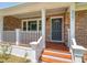 Inviting front porch with brick facade, white columns, and wood steps, leading to the front door at 327 Mcclain St, Charleston, SC 29407