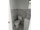 Compact bathroom featuring a toilet, sink with cabinet, and marble-tiled walls at 3307 Londonderry Rd, North Charleston, SC 29420