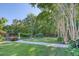 Well-manicured backyard with lush green grass, mature trees, garden beds, and black metal perimeter fence at 3751 St Ellens Dr, Mount Pleasant, SC 29466