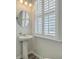 Charming half-bathroom featuring a pedestal sink, oval mirror, and natural light from a window with white shutters at 420 Oak View Way, Summerville, SC 29483