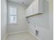 Practical laundry room with white cabinetry, tile floors, and a window with light-filtering shutters at 420 Oak View Way, Summerville, SC 29483