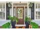 Inviting front entrance featuring a decorated door, sconces, and potted greenery at 5394 Clairmont Ln, North Charleston, SC 29420