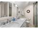 Bright bathroom featuring a double vanity with marble countertop, framed mirrors, and glass-enclosed shower at 5558 Green Dolphin Way, Kiawah Island, SC 29455