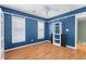 A modern bedroom features bright blue walls, a ceiling fan, a window with wood shutters, and custom shelving at 578 Delafield Dr, Summerville, SC 29483
