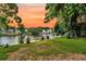 Scenic backyard view with waterfront access, lush green lawn, and colorful sunset at 721 Lake Frances Dr, Charleston, SC 29412