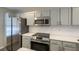 Close-up of a kitchen featuring stainless steel appliances, white countertops, and gray cabinets at 8721 Grassy Oak Trl, North Charleston, SC 29420