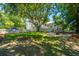 Backyard of a charming home featuring a manicured lawn, mature trees and a unique fire pit area at 11 49Th Ave, Isle of Palms, SC 29451