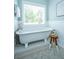 Bright bathroom boasts a freestanding tub under a window with wainscoting and stylish stool at 11 49Th Ave, Isle of Palms, SC 29451