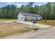 Newly constructed home exhibits a long driveway, tidy landscaping, and a classic white exterior with contrasting black roof at 112 Southsong Ln, Goose Creek, SC 29445