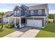 Attractive two-story home with blue siding, a two-car garage, and a charming front porch with outdoor seating at 120 Haverhill St, Summerville, SC 29486