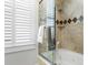Bathroom showcasing a glass-enclosed shower with jacuzzi tub and window with shutters at 150 Bee St # 308, Charleston, SC 29401