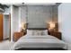 Modern bedroom showcasing a concrete accent wall, stylish lighting, and comfortable bed for a serene retreat at 150 Bee St # 308, Charleston, SC 29401