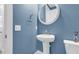 Stylish powder room featuring a blue accent wall, round mirror, modern sink, and toilet at 1541 Homecoming Blvd, Ravenel, SC 29470