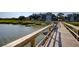 Scenic view of a wooden walkway extending over water to buildings near lush vegetation at 1551 Ben Sawyer Blvd # 4D, Mount Pleasant, SC 29464