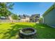 Large grassy backyard featuring a stone fire pit, ideal for outdoor gatherings and relaxation under the open sky at 1607 Roustabout Way, Charleston, SC 29414