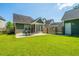 Well-maintained backyard featuring a dining set on a stone patio, screened porch, and grassy lawn at 1607 Roustabout Way, Charleston, SC 29414
