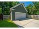 A detached garage features green siding, white doors, and a paved driveway amidst lush greenery at 1607 Roustabout Way, Charleston, SC 29414