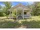 White cottage-style home with a covered front porch and mature trees in the yard, beneath a partly cloudy sky at 1736 Central Ave, Summerville, SC 29483