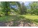 A cozy single-story home surrounded by mature trees on a large lot with lush green grass at 1736 Central Ave, Summerville, SC 29483