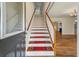 Entryway with staircase featuring wooden banister and red runners, leading to a bright living space at 2021 Lakeshore Dr, Charleston, SC 29412