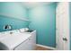 Laundry room with washer, dryer, white storage shelf, and blue walls at 234 S Lamplighter Ln, Summerville, SC 29486