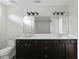 Bathroom with double vanity, large mirror, modern lighting fixtures, and dark wood cabinets at 302 Mossy Wood Rd, Summerville, SC 29483