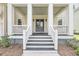 Detailed view of the front porch with white railings, dark wood steps, and elegant gray double doors at 3020 River Vista Way, Mount Pleasant, SC 29466