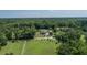 Expansive aerial view showcasing a unique round house with a backdrop of dense woodlands at 395 Summerset Ln, Summerville, SC 29483