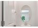 Bathroom with sleek oval mirror, white pedestal sink, and view to lush trees through a window at 425 W Respite Ln, Summerville, SC 29483