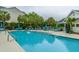 Sparkling swimming pool with lounge chairs and palm trees, surrounded by community buildings at 45 Scyamore Ave # 623, Charleston, SC 29407