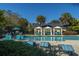 Sparkling swimming pool with lounge chairs, cabanas, palm trees, and community buildings under blue sky at 45 Scyamore Ave # 623, Charleston, SC 29407