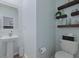 Powder room featuring a pedestal sink, toilet, floating shelves, and light blue walls at 505 Spanish Wells Road Rd, Summerville, SC 29486