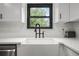 Close-up of a bright, white farmhouse sink with black faucet and white countertop by a black trimmed window at 518 Woodward Blvd, Summerville, SC 29483