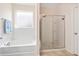 Bathroom featuring tiled tub, shower, and frosted window for optimal privacy at 536 Man O War Ln, Moncks Corner, SC 29461