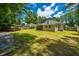Large, fenced backyard with a lush lawn, mature trees, and a covered pergola at 687 Ponderosa Dr, Charleston, SC 29414