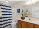 Clean bathroom with a blue striped shower curtain, white tiling, and ample counter space at 7 Beach Club Villas, Isle of Palms, SC 29451