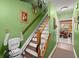 Hallway with wooden stairs, chair lift, green painted walls and entrance into dining room and kitchen at 8475 N Scotts Mill Dr, North Charleston, SC 29420