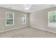 Empty, carpeted bedroom with natural light, ceiling fan, and two large windows facing the street at 9253 N Moreto Cir, Summerville, SC 29485