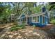Beautiful exterior view of home featuring blue siding, screened in porch, and surrounding mature trees at 10 Chapman Ave, Isle of Palms, SC 29451