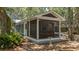 Close up of the screened-in porch, featuring a seating area and bird bath, surrounded by lush landscaping at 10 Chapman Ave, Isle of Palms, SC 29451