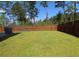 The spacious backyard features a climbing dome, lush grass, and a tall privacy fence at 103 Granton Edge Ln, Summerville, SC 29486