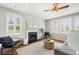 Cozy living room with a fireplace, ceiling fan, large windows, and stylish decor at 123 Gaslight Blvd, Summerville, SC 29483