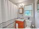 Bright bathroom featuring vanity with red wood cabinet, mirror, window and bathtub with shower at 131 Harvey Ave, Goose Creek, SC 29445