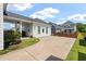 Rear exterior showcasing a charming home design with a covered patio, landscaped yard, and a spacious driveway at 1894 Brittlebush Ln, Johns Island, SC 29455