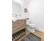 Bathroom featuring wood style vanity, square mirror, decorative basket, and toilet with black and grey rug at 2020 Piper Dr, Charleston, SC 29407