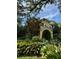 Exterior shot of home featuring an arched entryway, mature trees, and lush landscaping at 2066 Wappoo Dr, Charleston, SC 29412