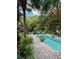 A backyard pool is surrounded by a brick patio, mature trees, and tropical landscaping at 2066 Wappoo Dr, Charleston, SC 29412