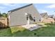 A view of the home's siding, back door, and small patio in a grass-covered backyard at 210 Wildberry Ln, Goose Creek, SC 29445