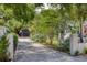 Long concrete driveway leads to a detached garage, enhanced by mature trees, landscaping, and a charming home at 216 Freeman St, Mount Pleasant, SC 29464