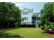 Expansive lush green backyard with white siding, mature trees, and large screened in porch at 31 Seagrass Ln, Isle of Palms, SC 29451